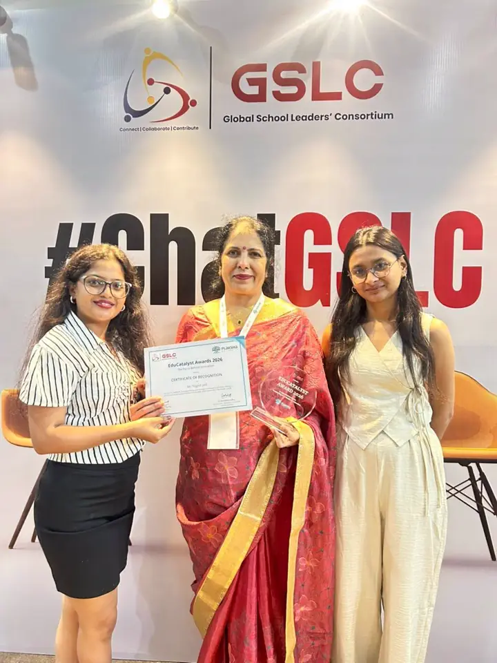 Mrs. Yogesh Jadli holding her certificate in front of the GSLC backdrop, with two members of the organising team