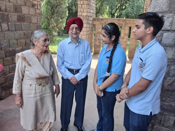 Two students in school uniform talking with an elderly couple under brick arches
