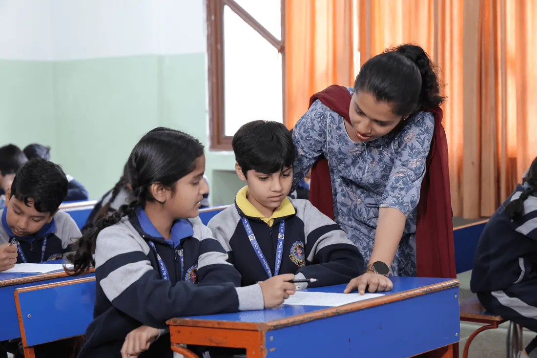 A teacher helping students at their desks in a KIS classroom